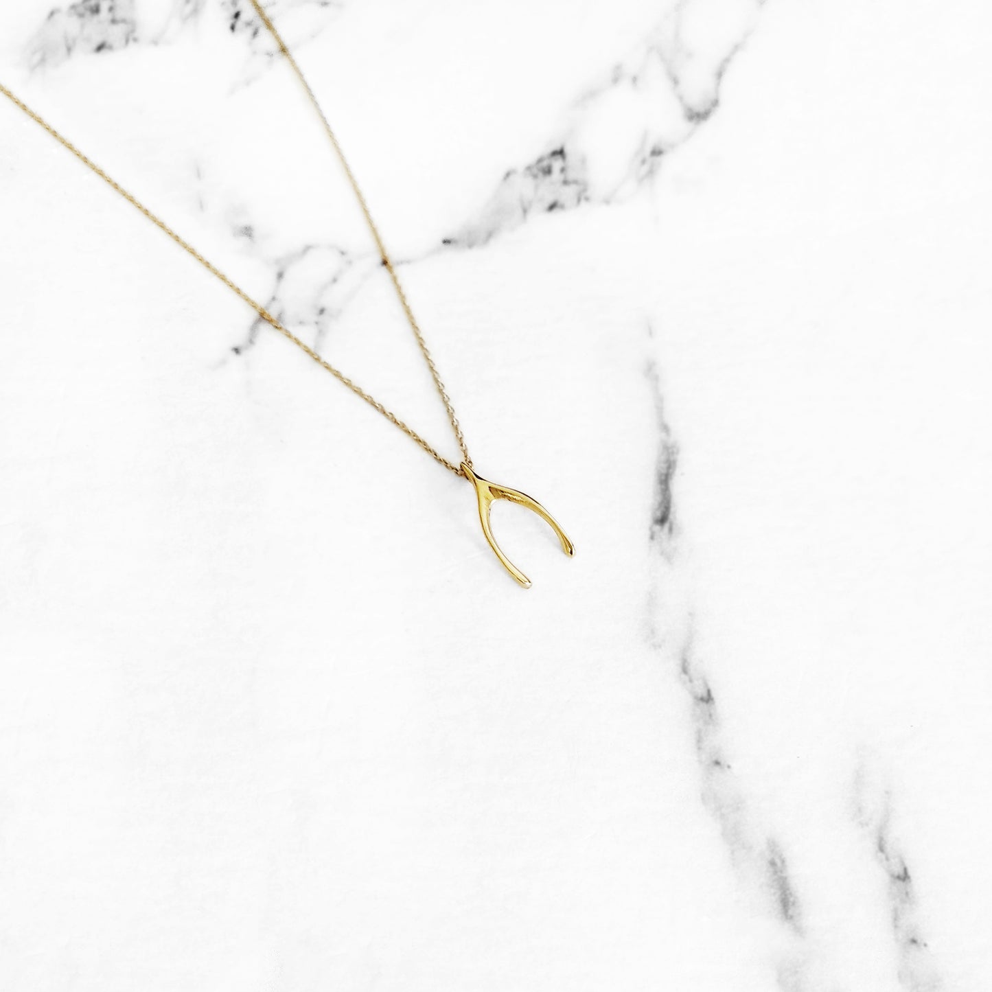 dainty solid yellow gold necklace with a tiny wishbone charm