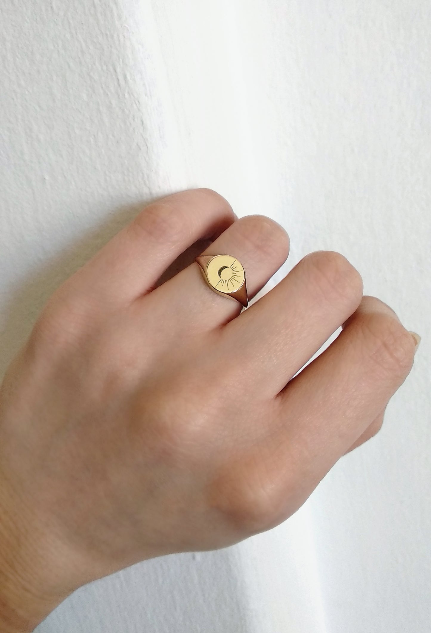 female wearing solid yellow gold round signet ring engraved with the sun and moon on her ring finger