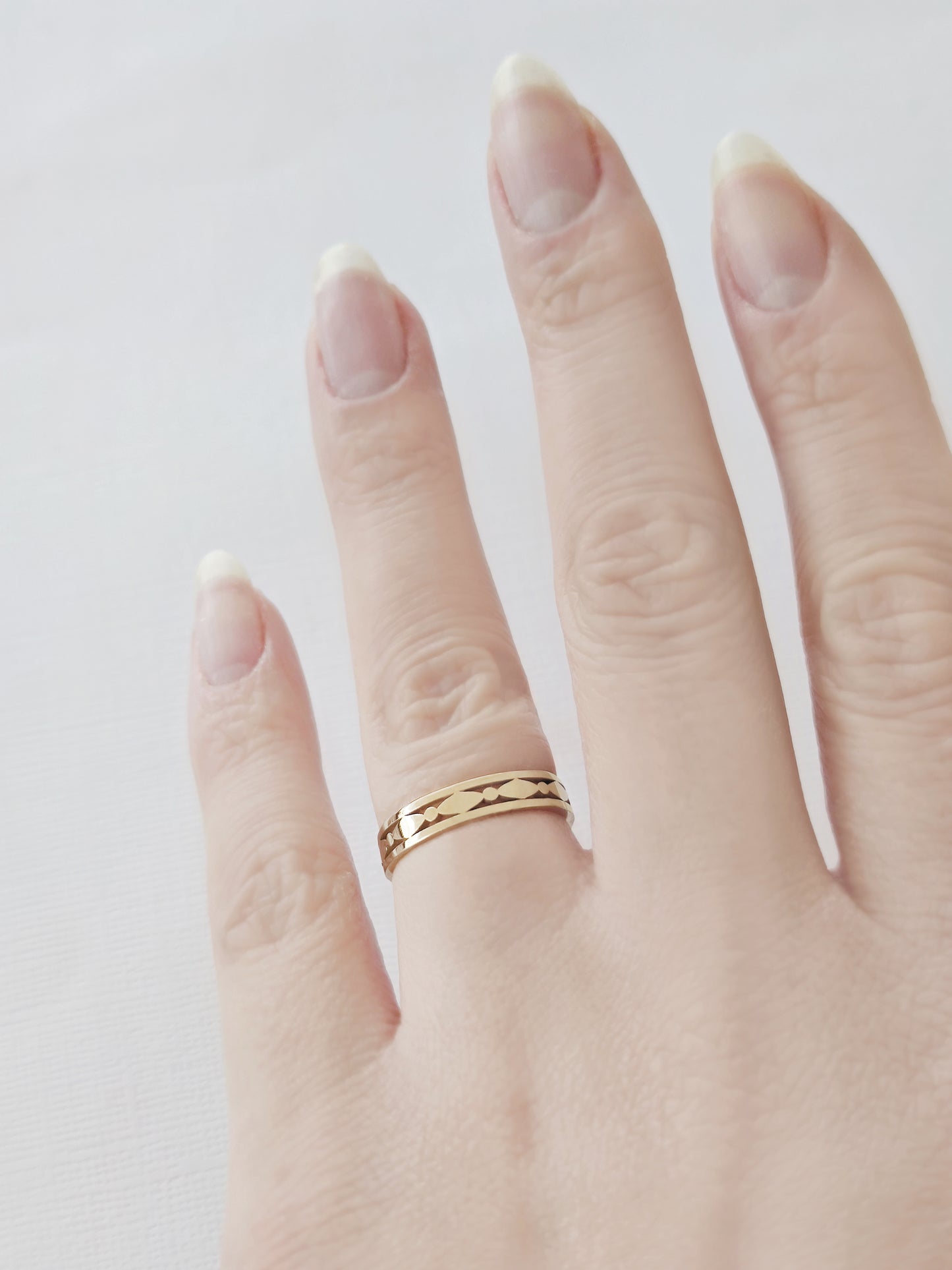 female hand wearing a solid yellow gold art deco band