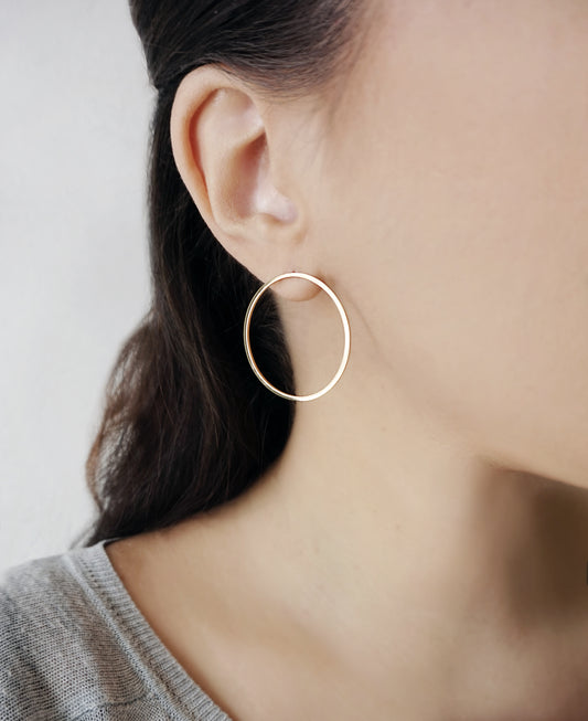 female wearing big open circle hoop stud earrings in solid yellow gold