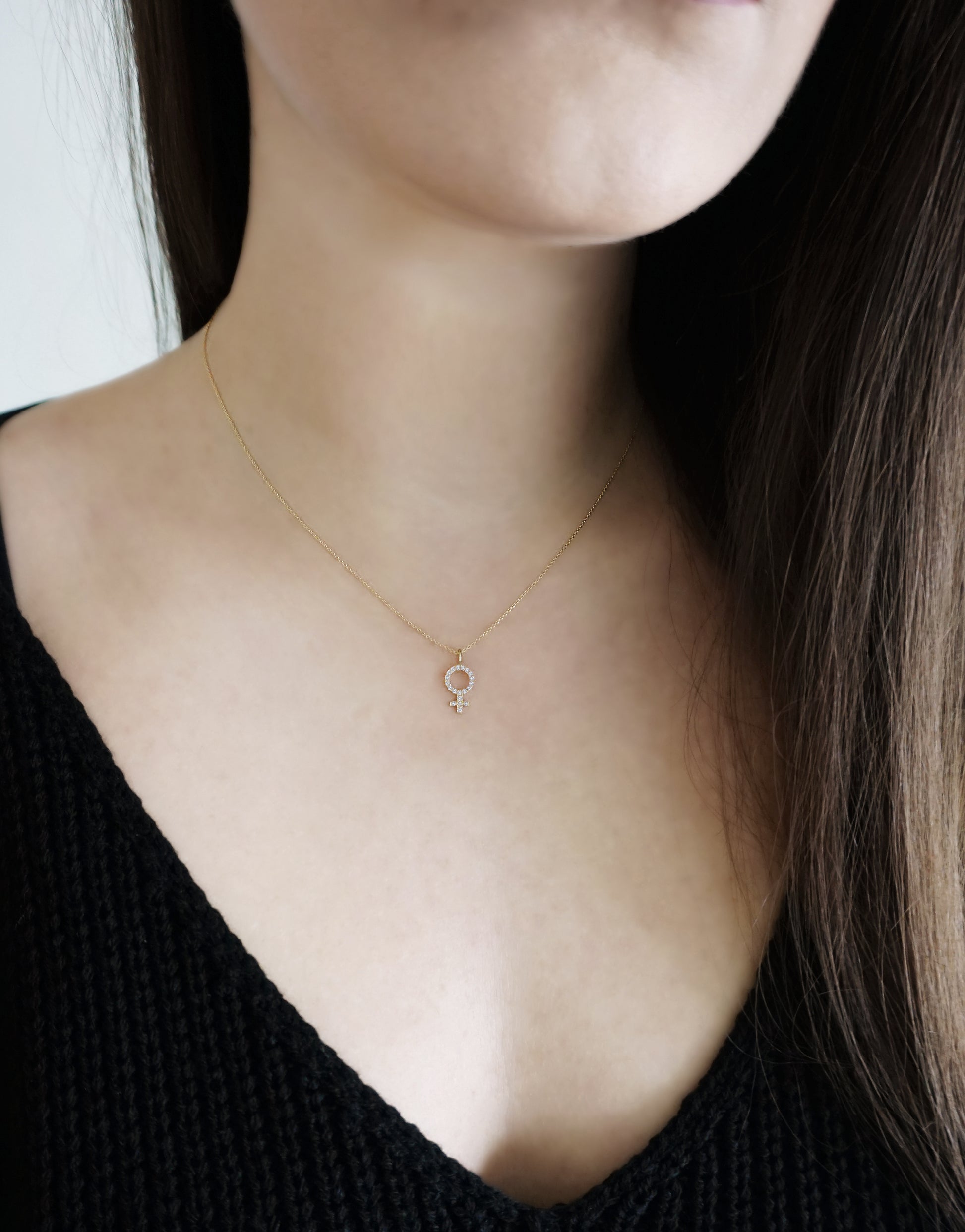 woman wearing solid yellow gold necklace with a female venus symbol charm set with white diamonds