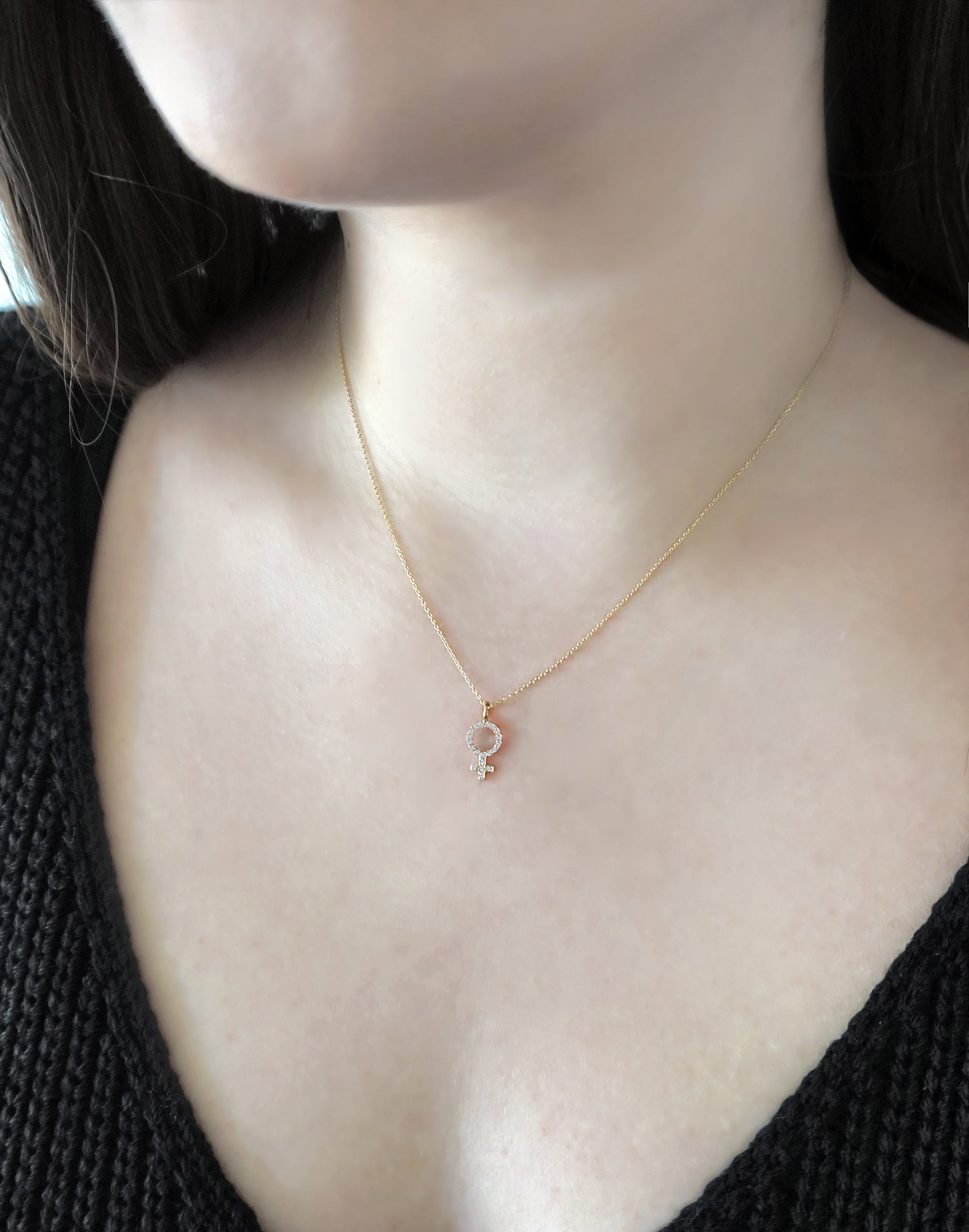 woman wearing a  yellow gold necklace with a female venus symbol charm set with white diamonds