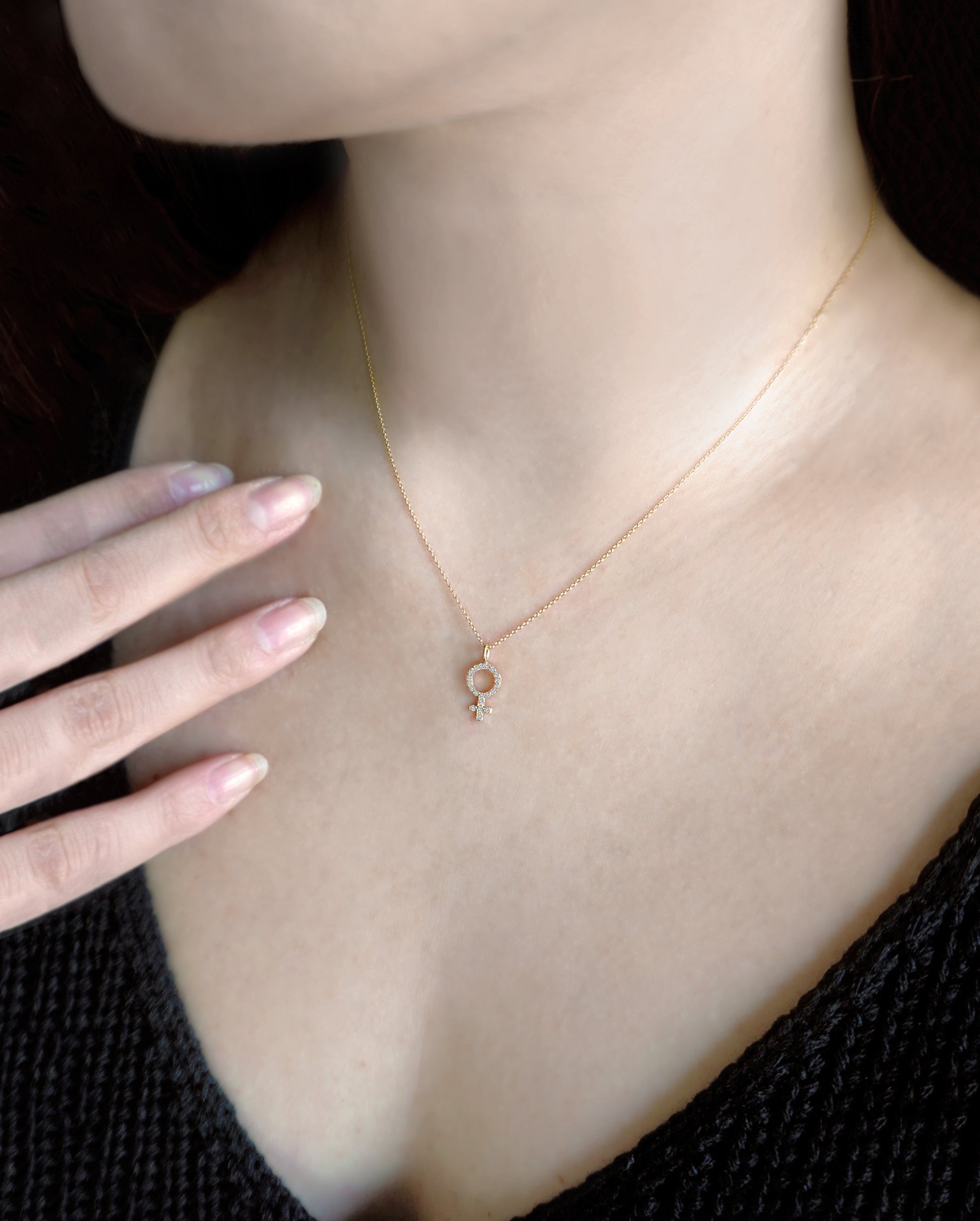 female wearing solid yellow gold necklace with a female venus symbol charm set with white diamonds