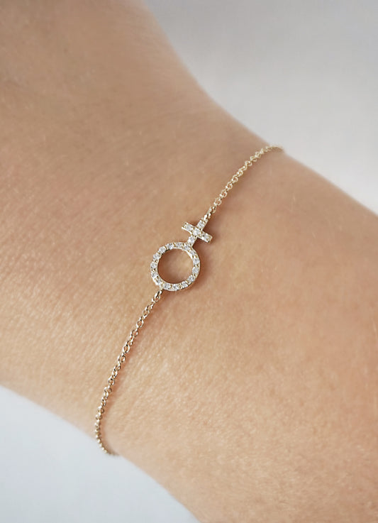 woman's wrist wearing a solid yellow gold bracelet with a venus female symbol charm set with tiny diamonds