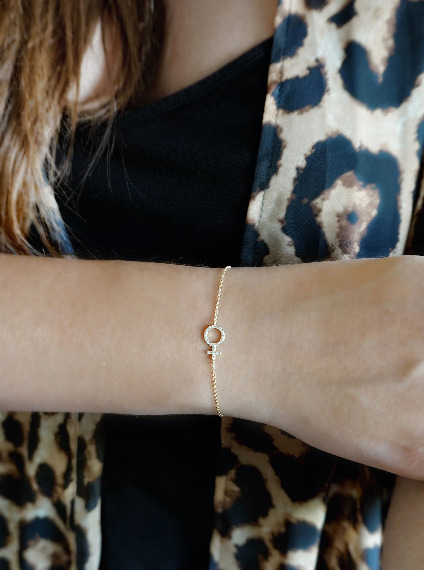 female wearing a dainty yellow gold bracelet with a venus female symbol charm set with tiny diamonds