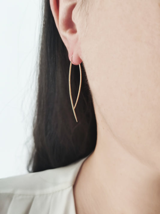 woman wearing a solid yellow gold swing threader earring with one matte curved bar and one longer polished curved bar