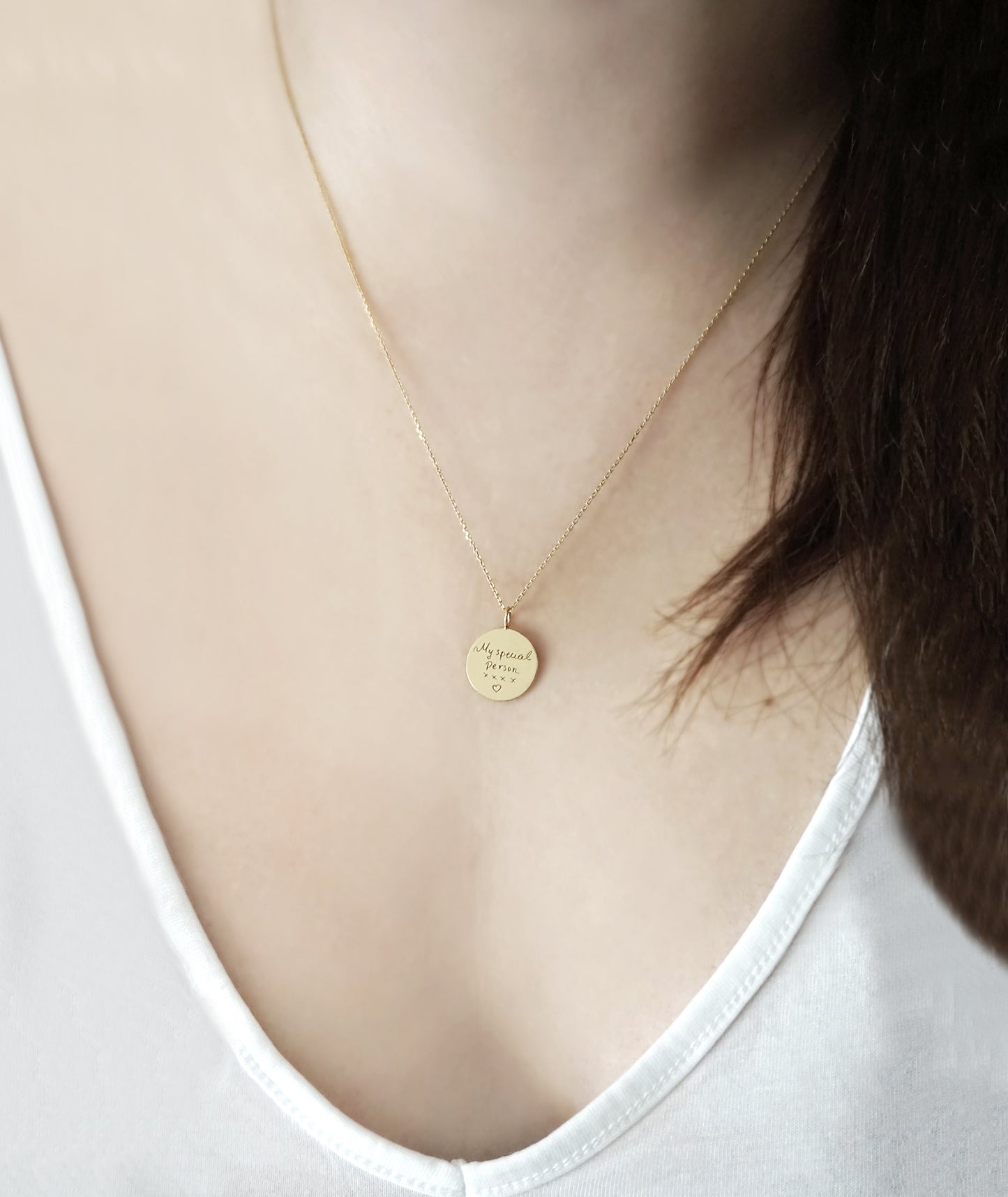 gold necklace with a round pendant with custom handwritten engraving worn by a female model