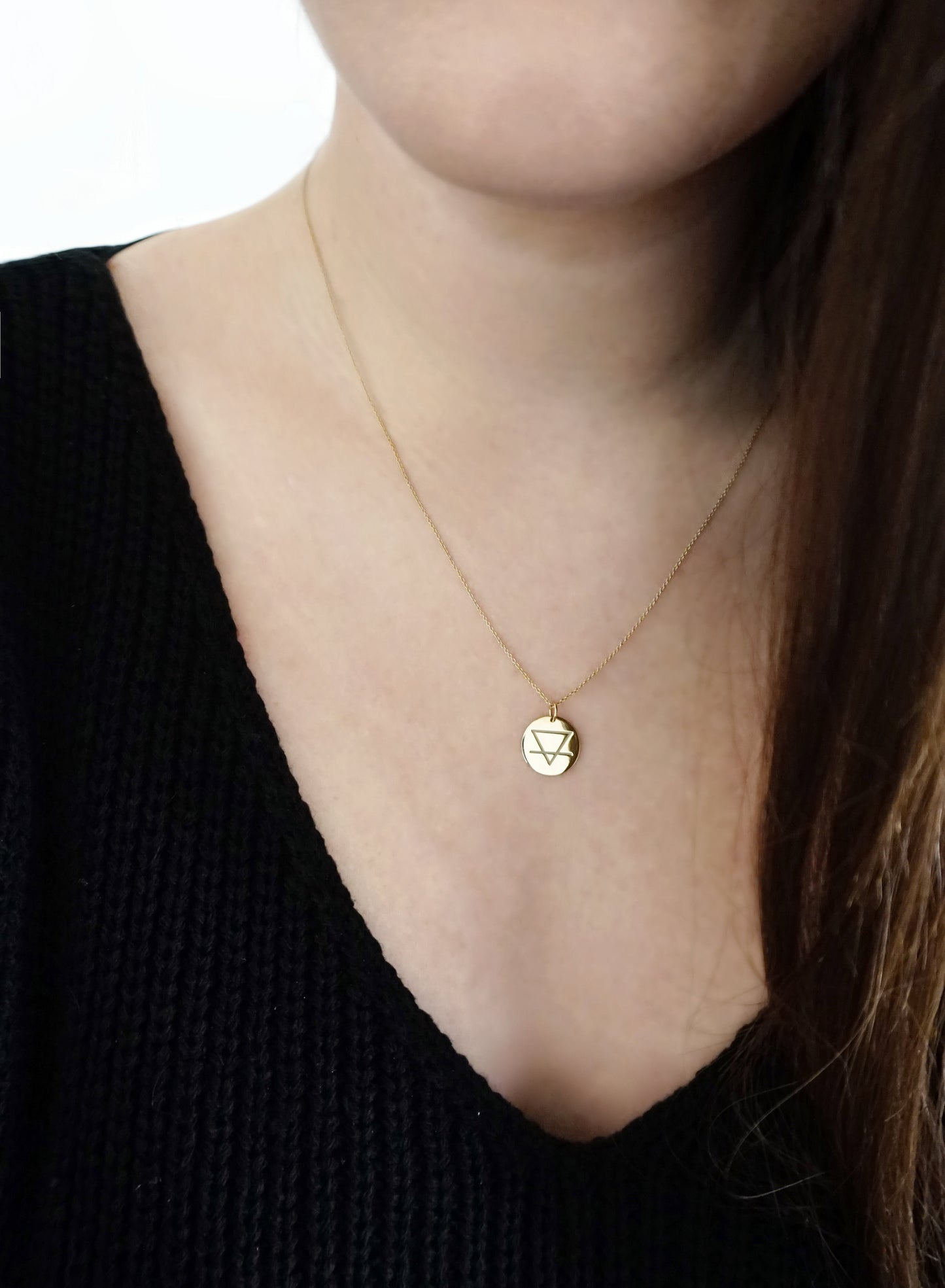 woman wearing a yellow gold necklace with a 14mm disc pendant engraved with the earth element
