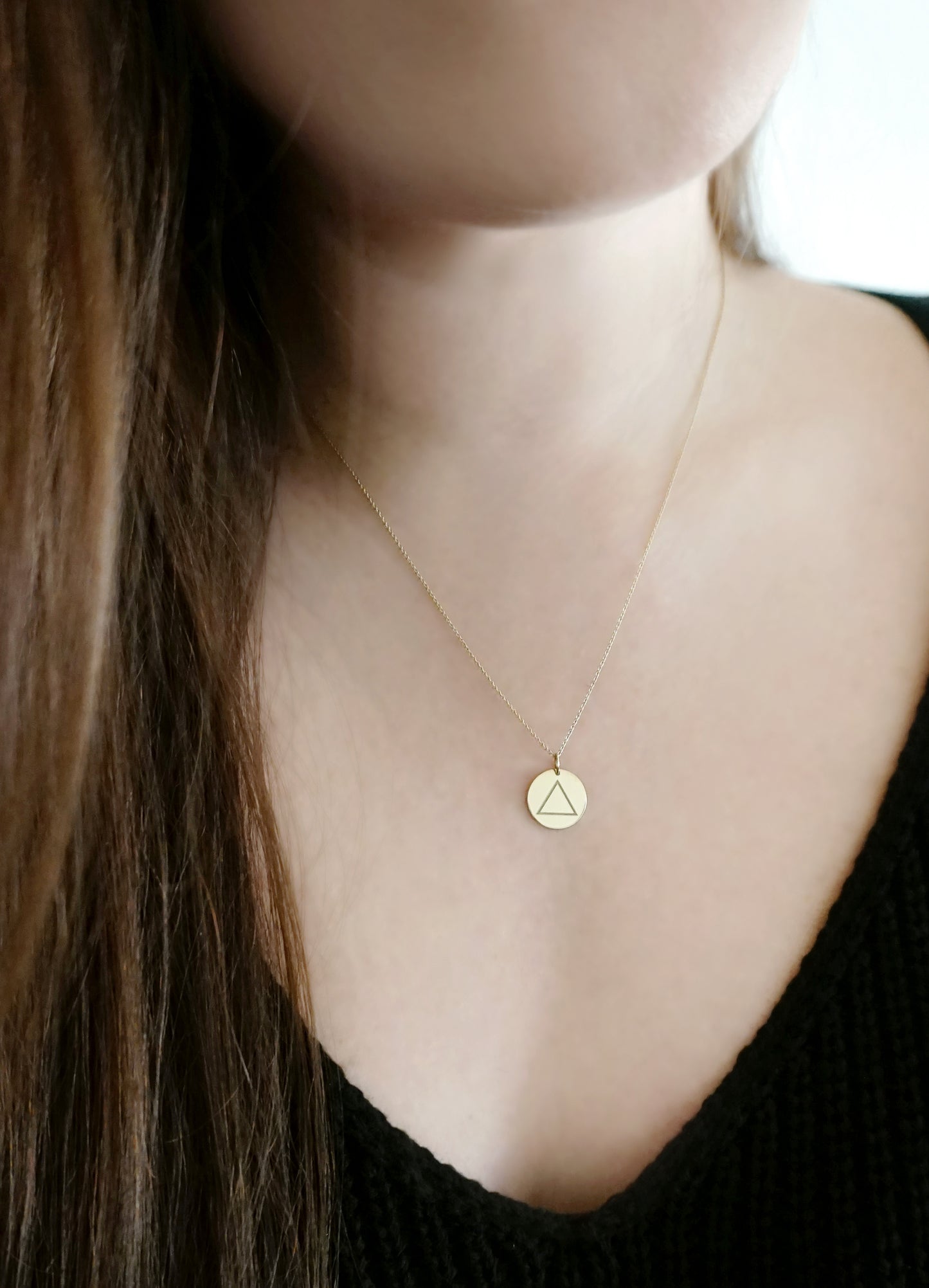 woman wearing a yellow gold necklace with a 14mm disc pendant engraved with the fire element symbol
