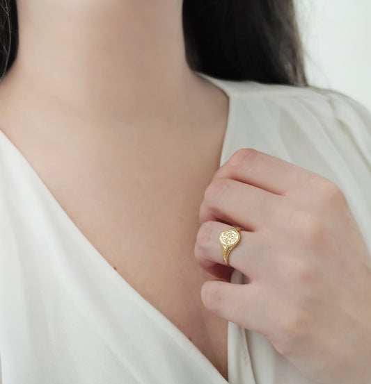 female wearing gold floral signet ring on her ring finger