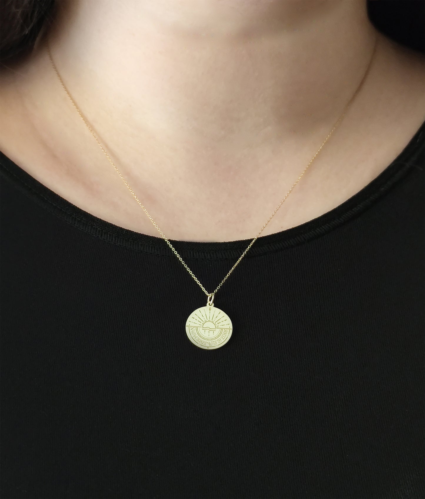 close up of a woman's neck wearing a gold disc pendant necklace engraved with a compass and personalized coordinates