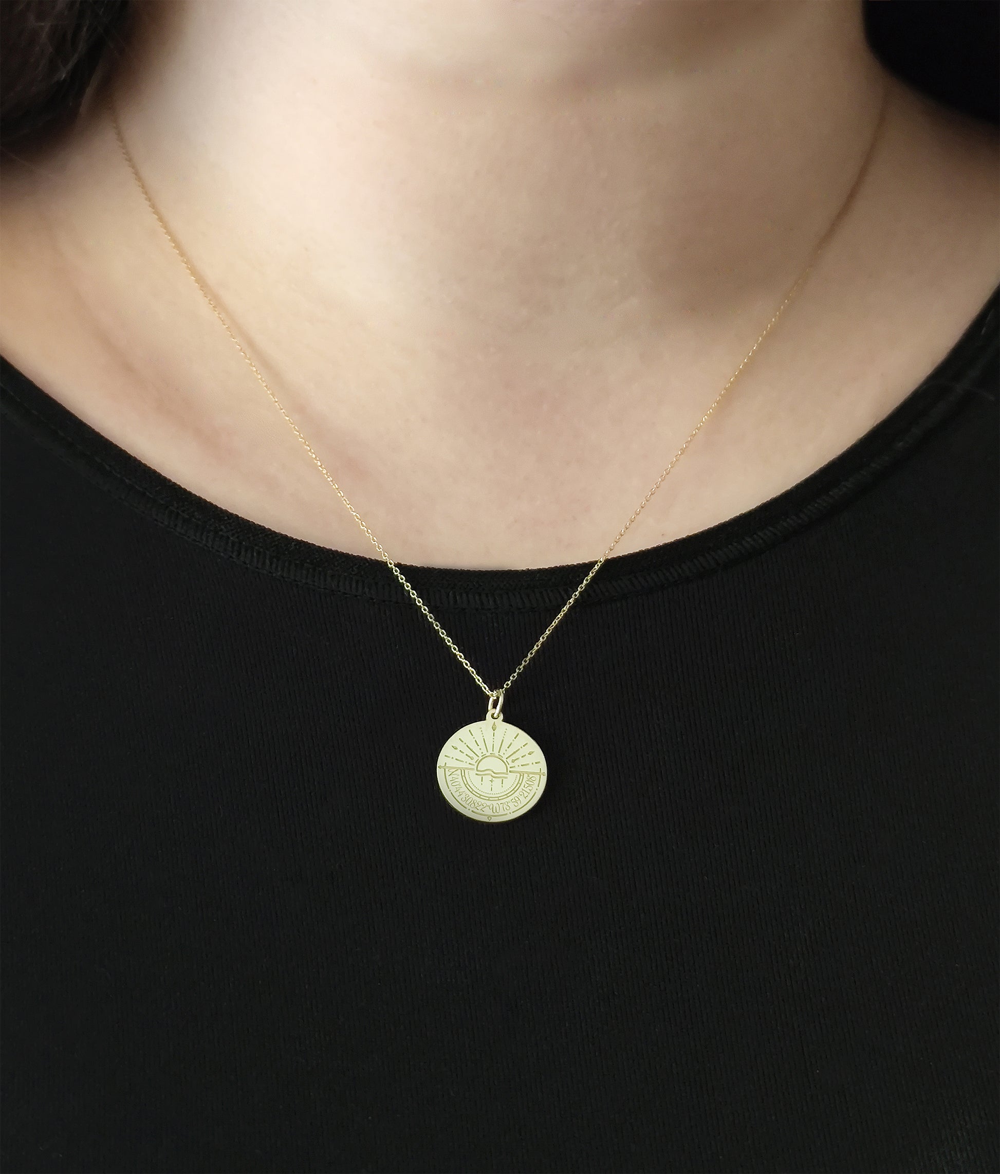 close up of a woman's neck wearing a gold disc pendant necklace engraved with a compass and personalized coordinates