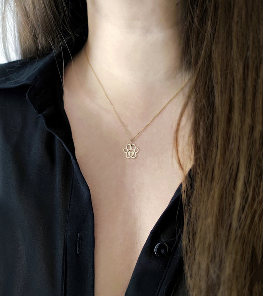 female wearing gold necklace with a dog paw print pendant engraved with a monogram