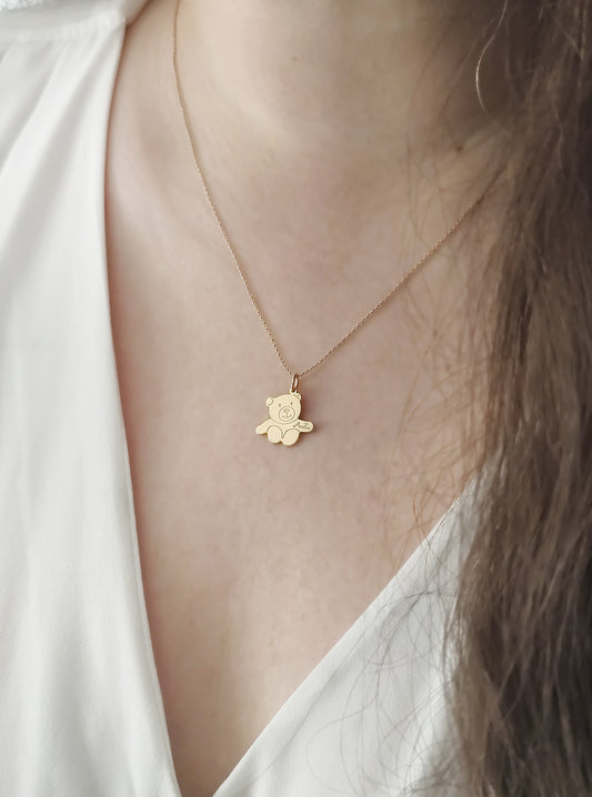 woman wearing gold necklace with a small teddy bear shaped pendant with open arms engraved with a baby's name