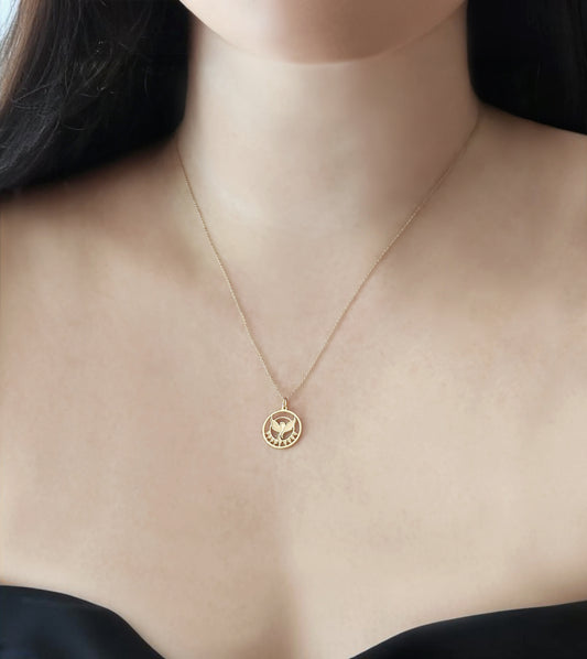 close up of a woman's neck wearing a yellow gold necklace with a cutout phoenix firebird pendant rising from flames