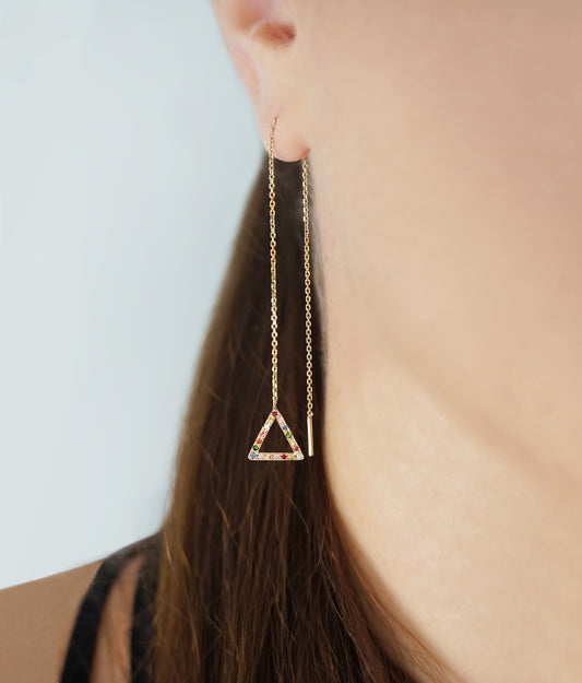 woman wearing a threader earring with a small triangle at the end set with rainbow sapphires and made in solid yellow gold