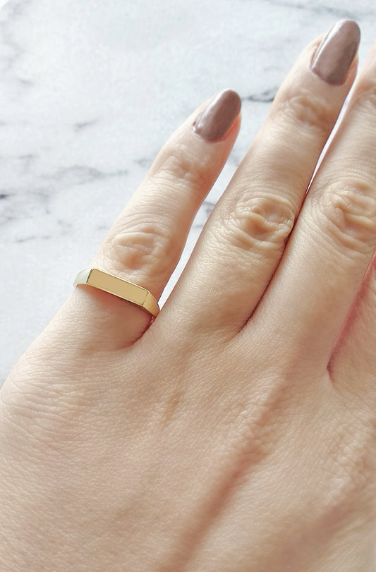 female hand wearing solid yellow gold rectangle bar signet ring on her pinky