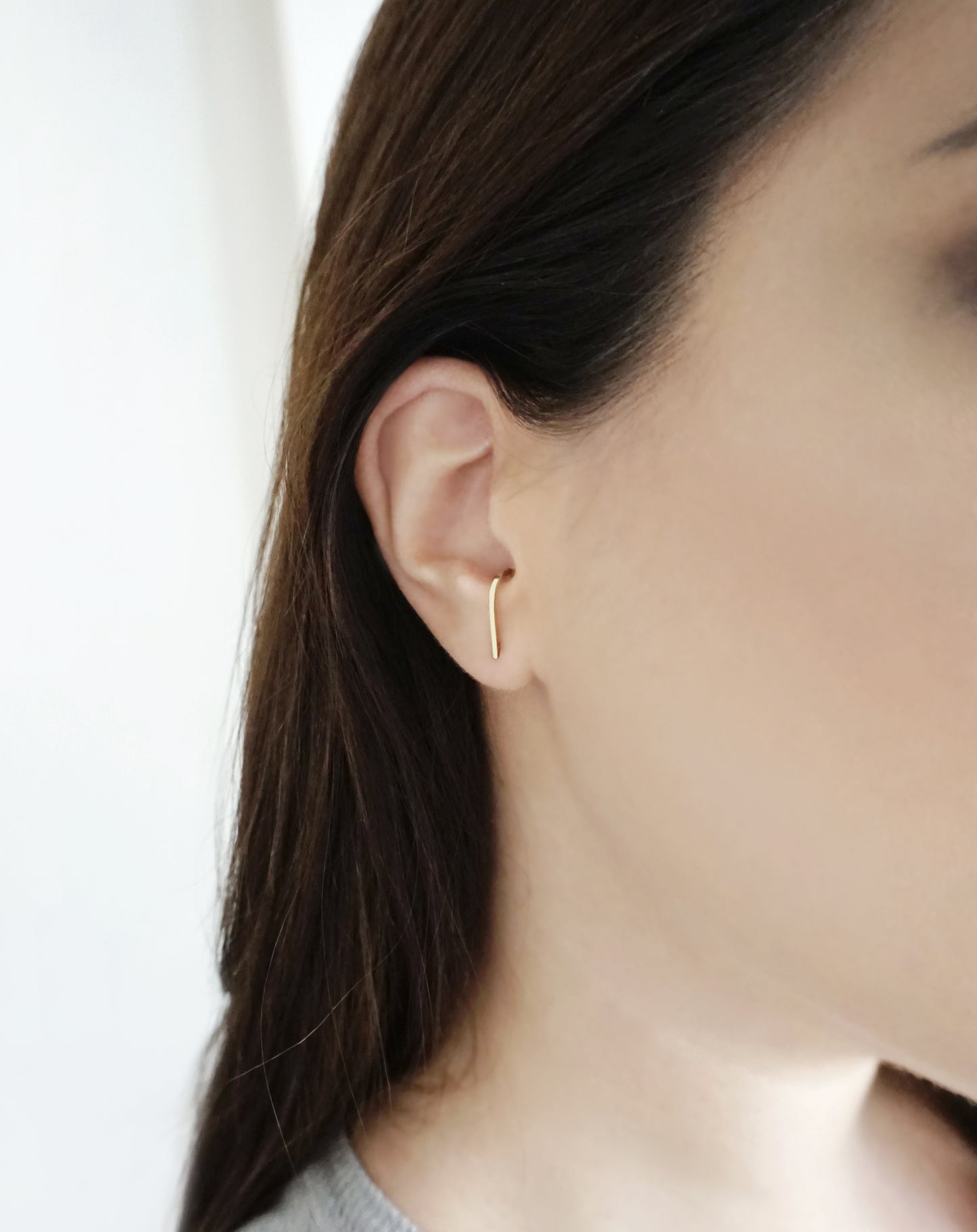 female wearing a solid yellow gold suspender hook cuff earring