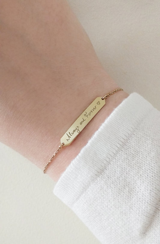 female wrist wearing gold personalized bracelet with a hexagon bar engraved with custom handwritten message