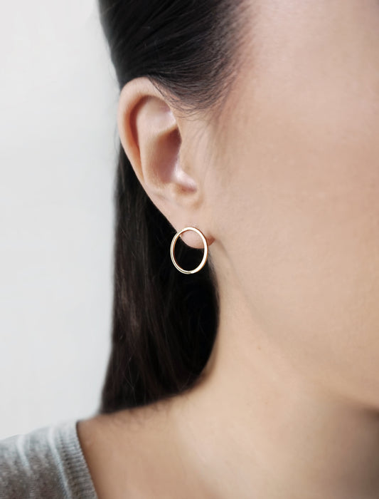 female wearing small open circle hoop stud earrings in solid yellow gold