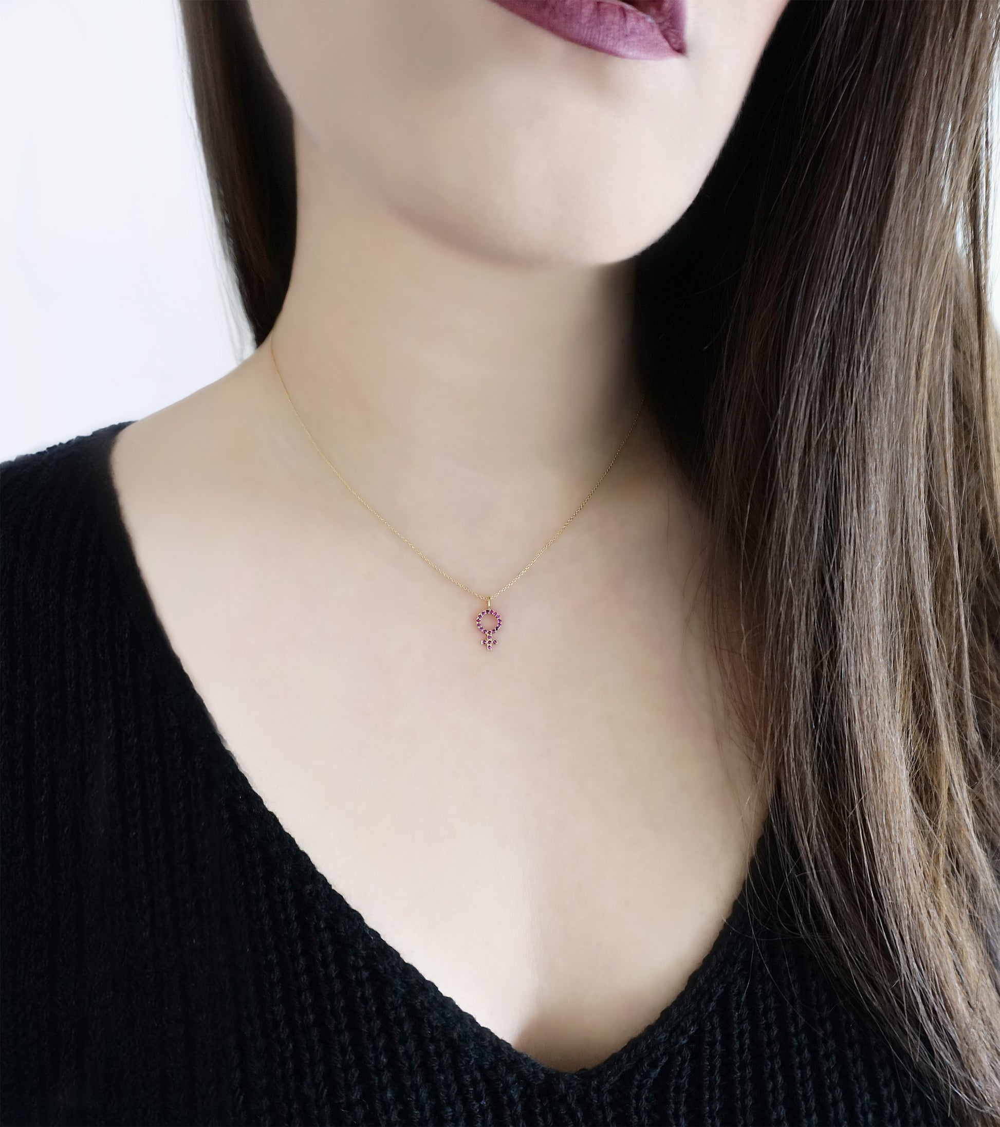female wearing a dainty gold necklace with a small venus female symbol pendant set with Rubies