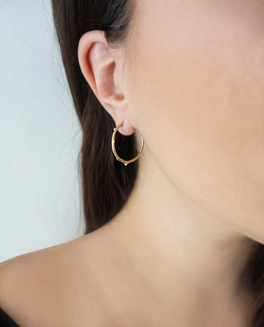 female wearing solid gold twig branch open hoop earrings