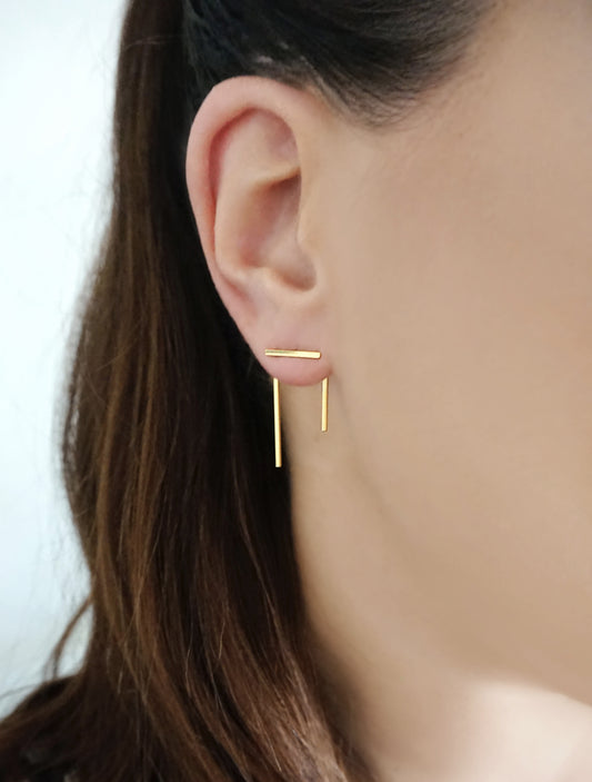 woman wearing an ear jacket consisting of a simple line/bar on the front of the earlobe and a pi shaped line on the back of the earlobe