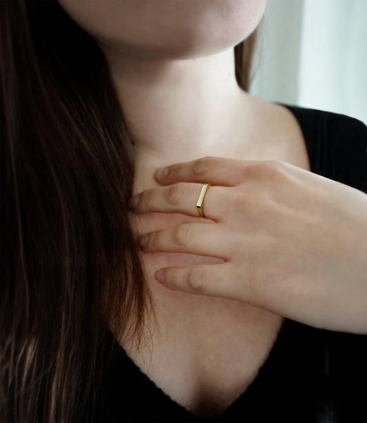 female wearing thin bar ring on her middle finger