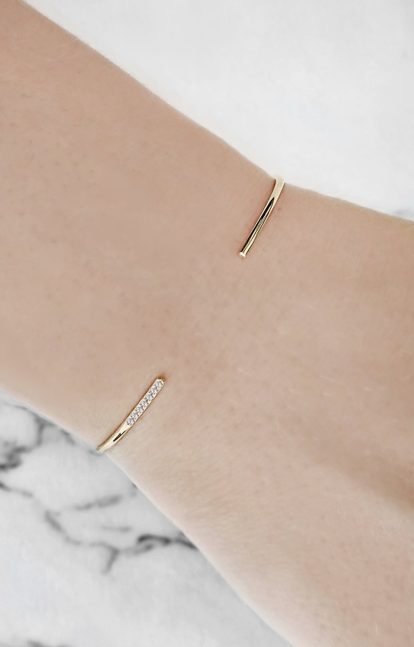 female wrist wearing gold thin cuff bracelet set with seven white diamonds