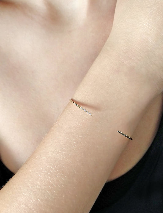 female wearing solid gold thin open bangle set with seven white diamonds
