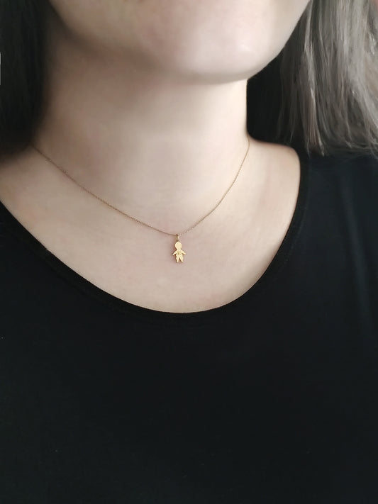 close up of a woman's neck wearing a gold necklace with a tiny boy outline charm engraved with a monogram