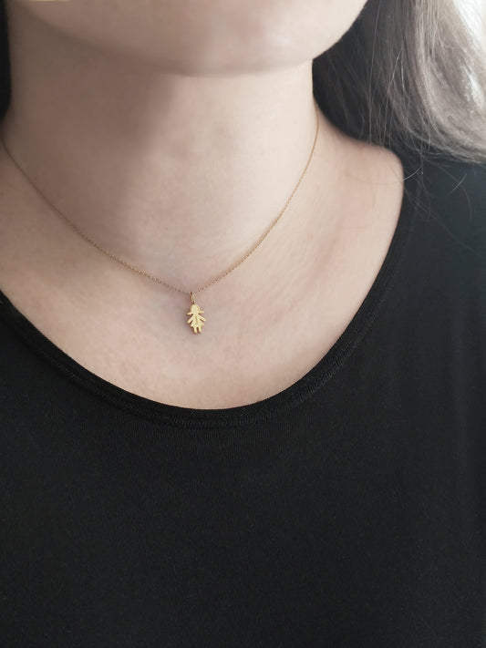 close up of a woman's neck wearing a gold necklace with a tiny girl charm engraved with a monogram