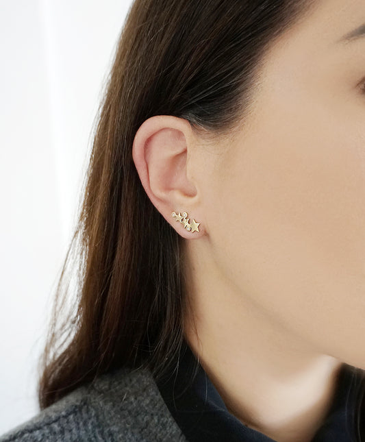 female wearing pair solid yellow gold triple star climber earrings with three tiny diamonds