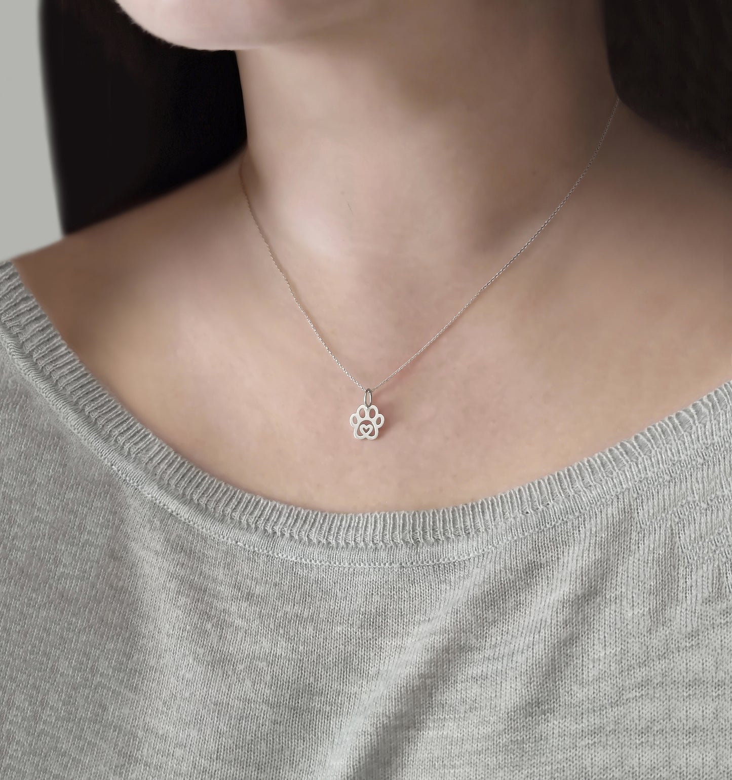 Female wearing white gold necklace with a tiny dog paw print pendant with a heart in the center
