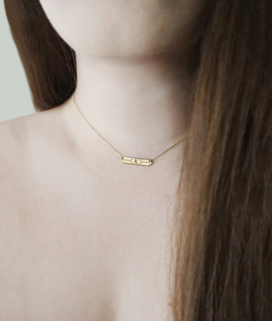female wearing a solid gold hexagon bar necklace set with white diamonds and personalized with a custom monogram