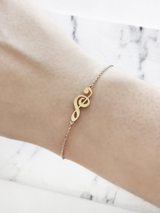 female wrist wearing gold treble clef music charm bracelet