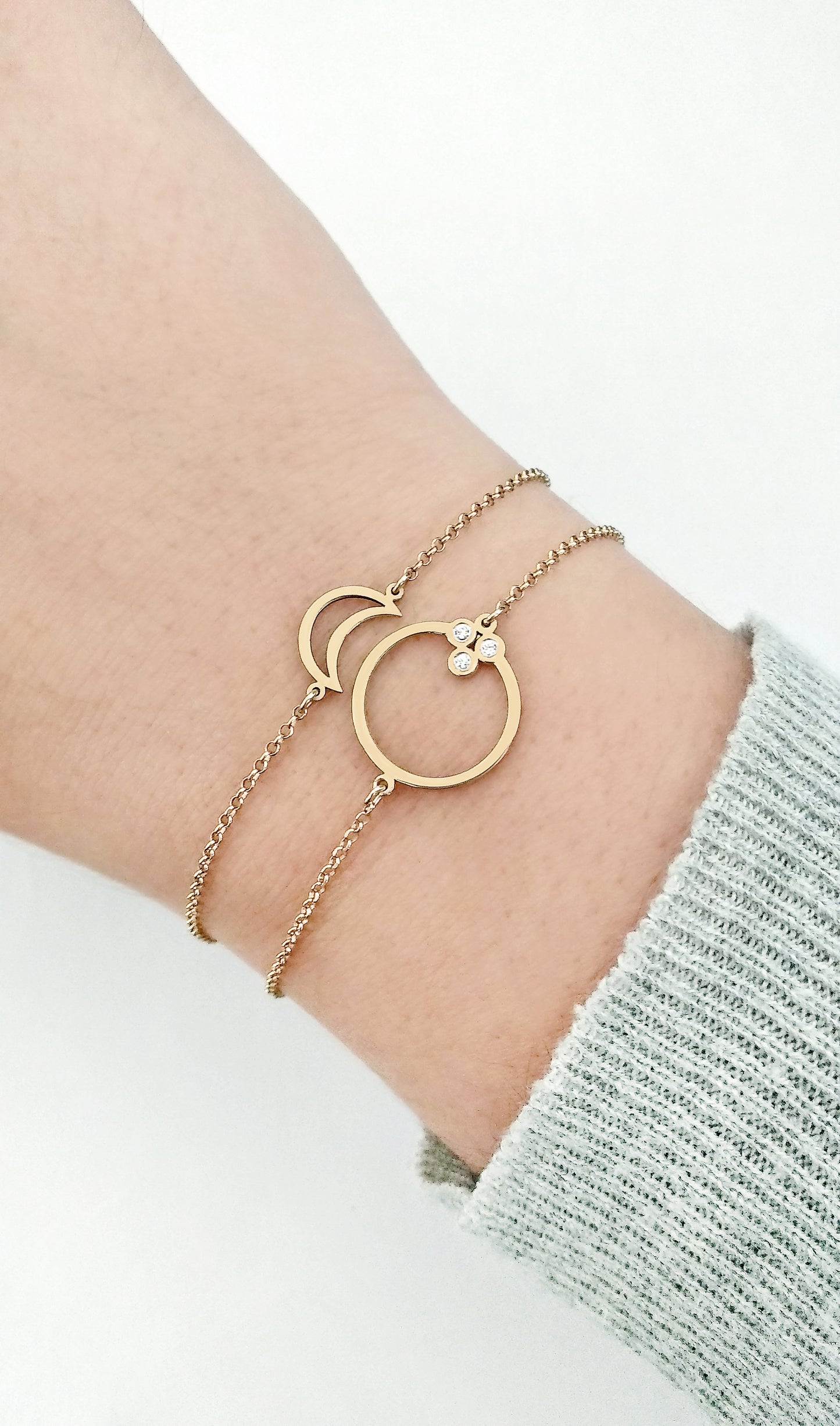 female wrist wearing a solid gold circle karma charm bracelet set with three tiny diamonds and a crescent moon charm bracelet