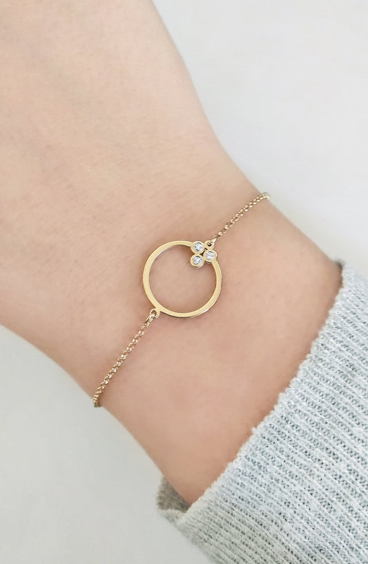 female wrist wearing solid gold circle karma charm bracelet set with three tiny diamonds