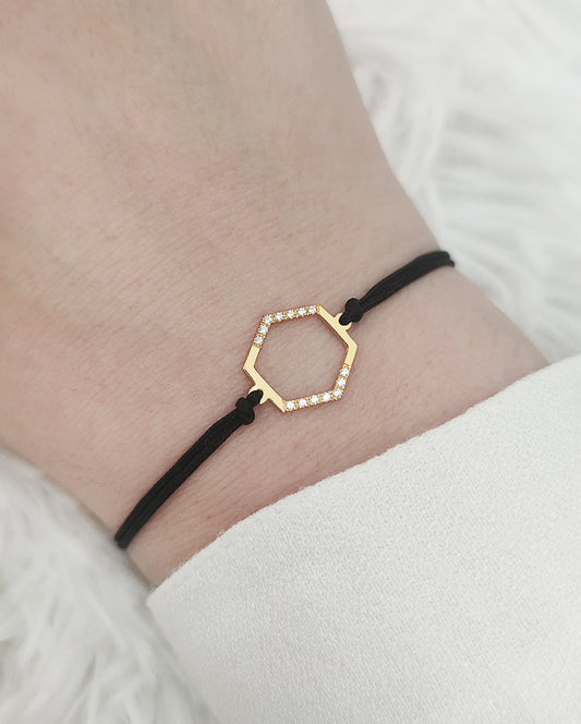female wrist wearing solid yellow gold macrame bracelet with a small hexagon charm set with 12 white diamonds