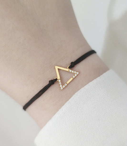 woman's wrist wearing solid yellow gold macrame bracelet with a small triangle charm set with 12 white diamonds on its two corners