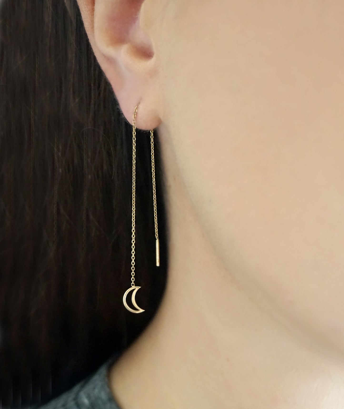 close up of a woman's ear wearing gold threader pull through earring with tiny a crescent moon