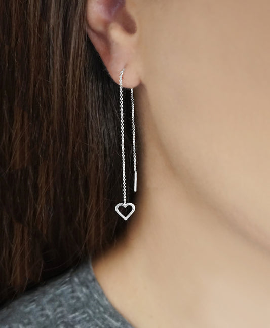 woman wearing a solid white gold threader pull through earring with tiny heart