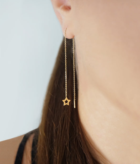 woman wearing yellow gold threader pull through earring with a tiny star