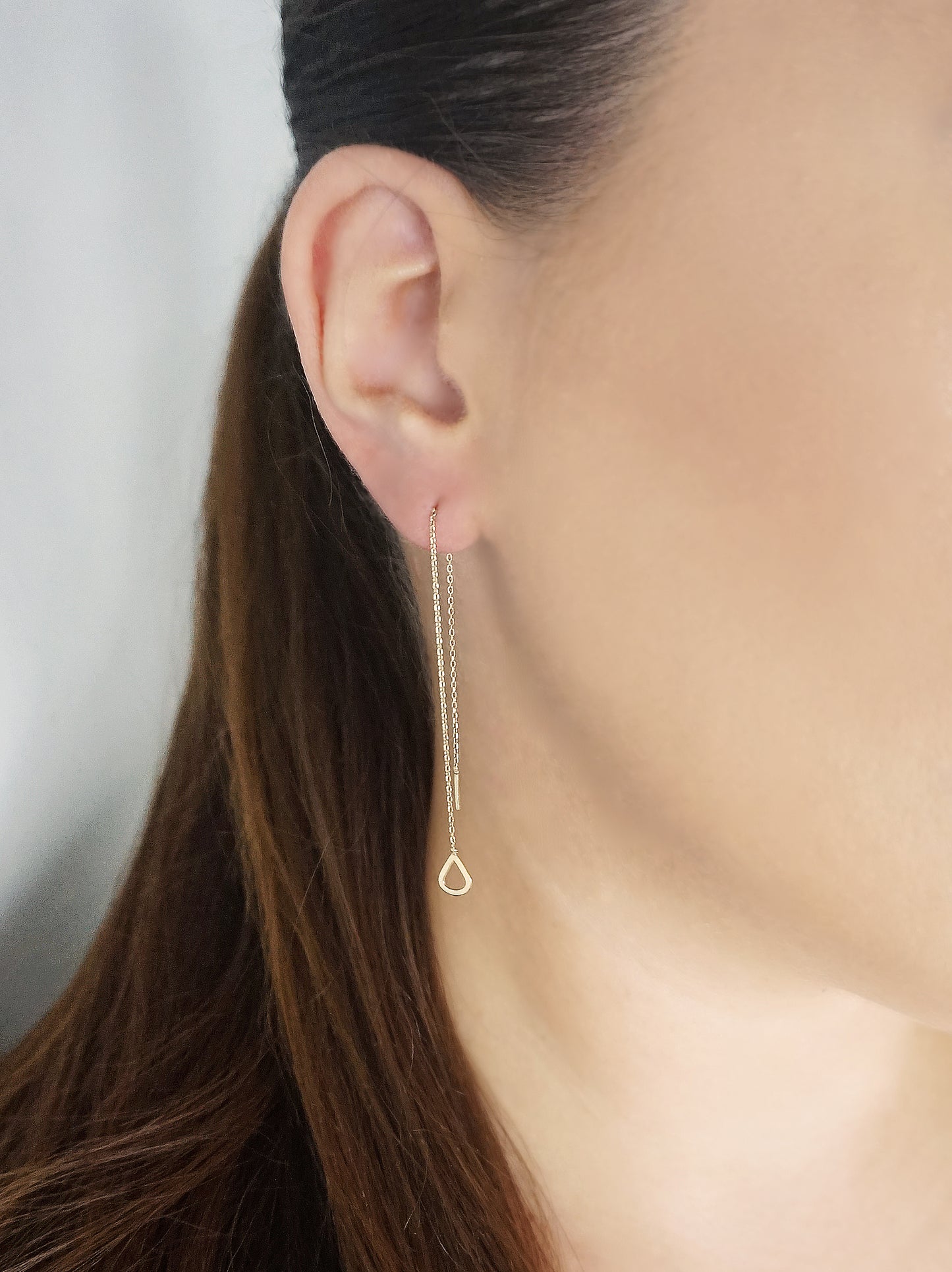 female wearing yellow gold threader pull through earring with a tiny teardrop