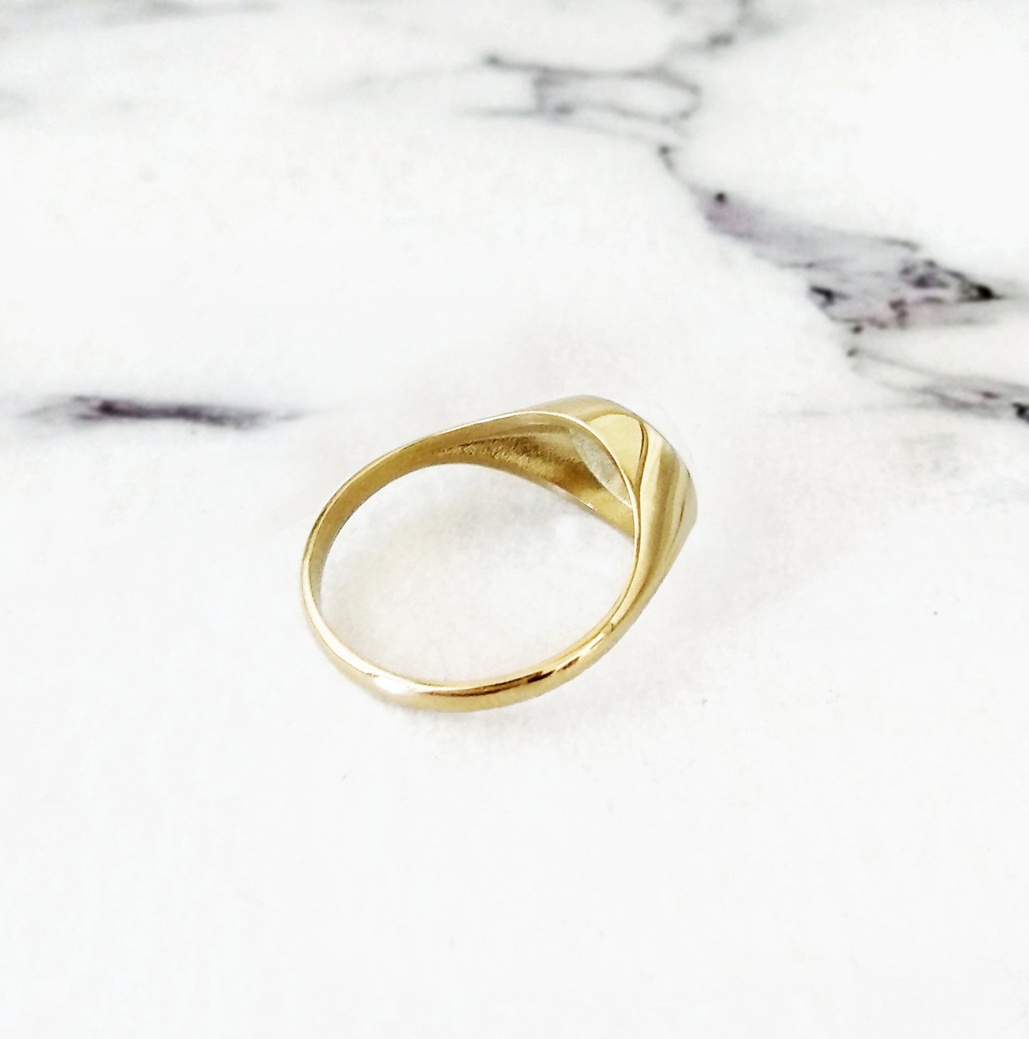 view of the semi hollow back of a solid yellow gold dainty oval signet ring set with star polaris diamond