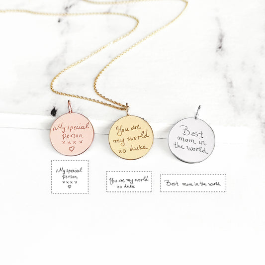 Three round pendants with personalized handwriting engravings on a marble background