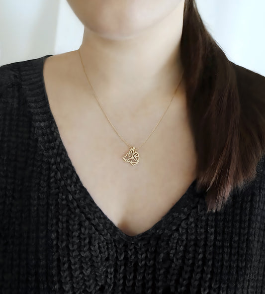 woman wearing a yellow gold necklace with a wolf pendant inspired by origami