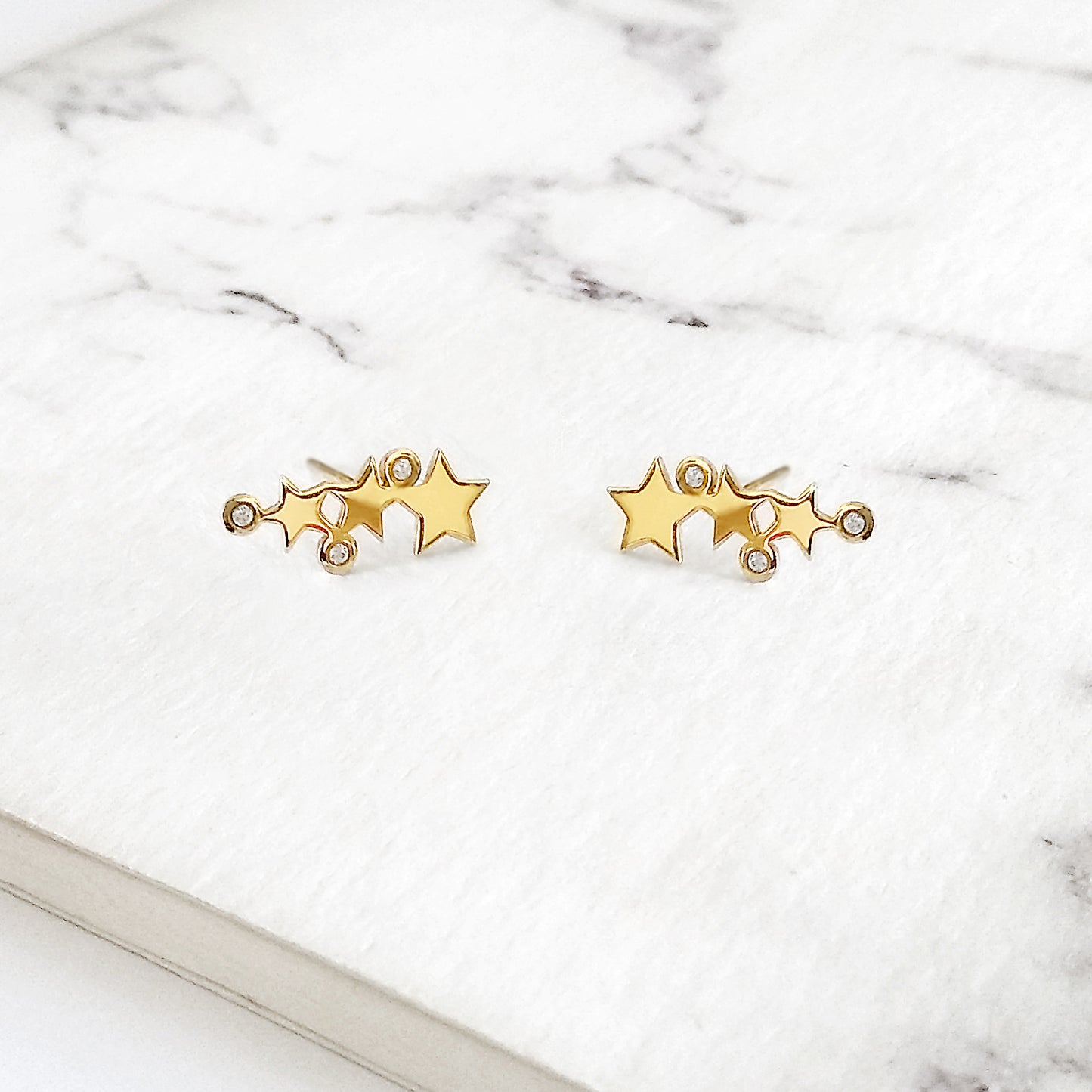 pair of yellow gold triple star climber earrings with three tiny diamonds