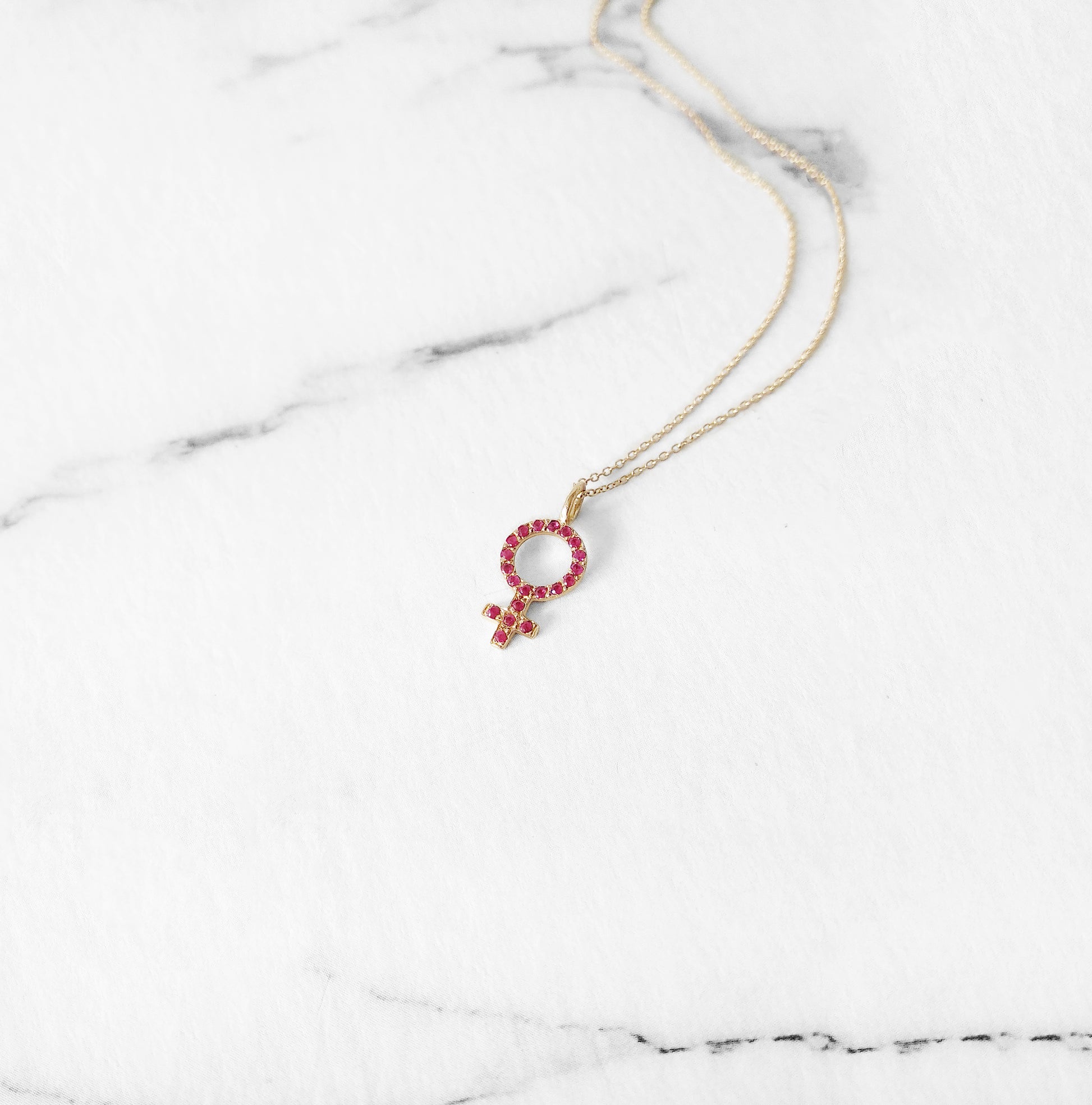 14K yellow gold necklace with a small venus female symbol pendant set with Rubies
