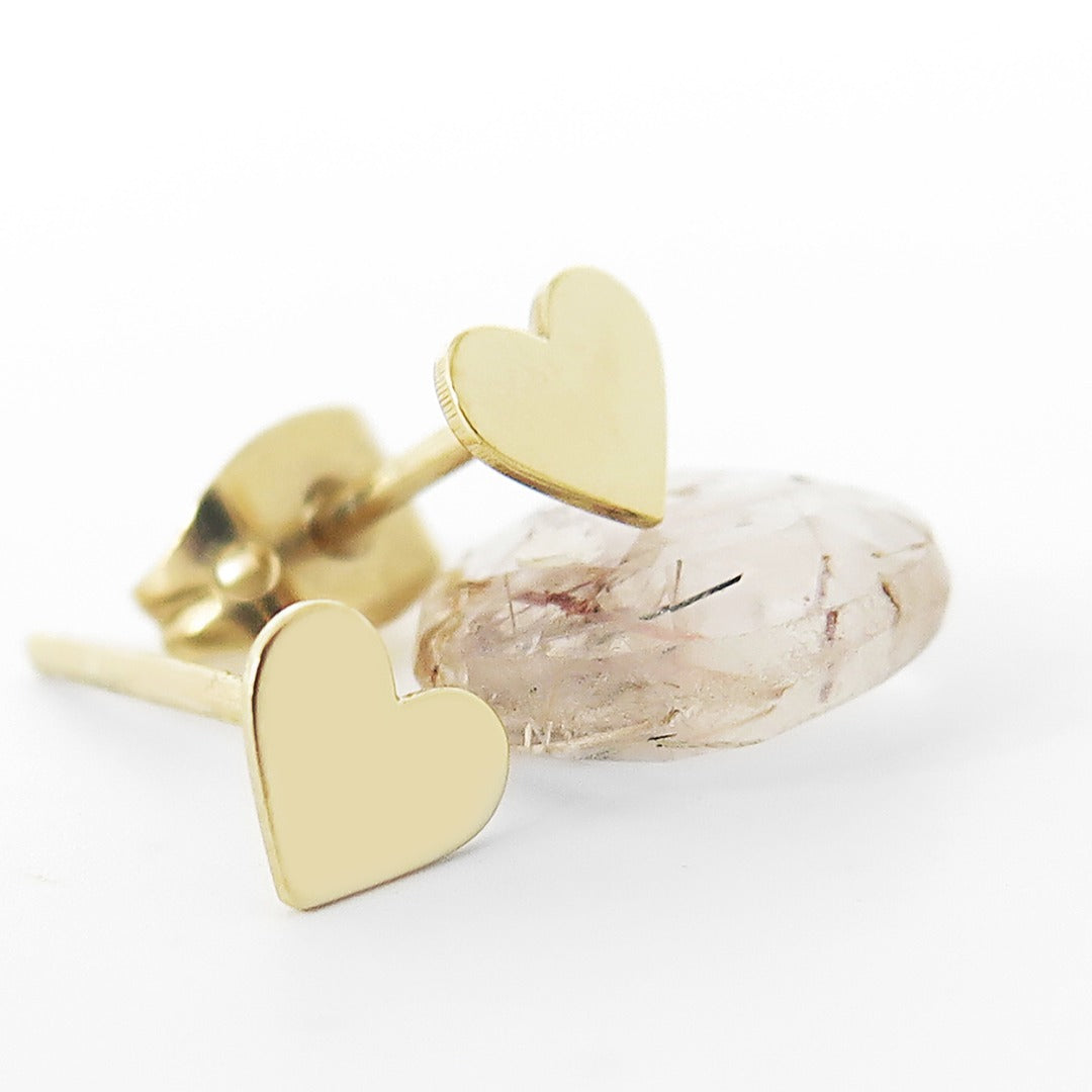 Gold heart-shaped stud earrings on a white background